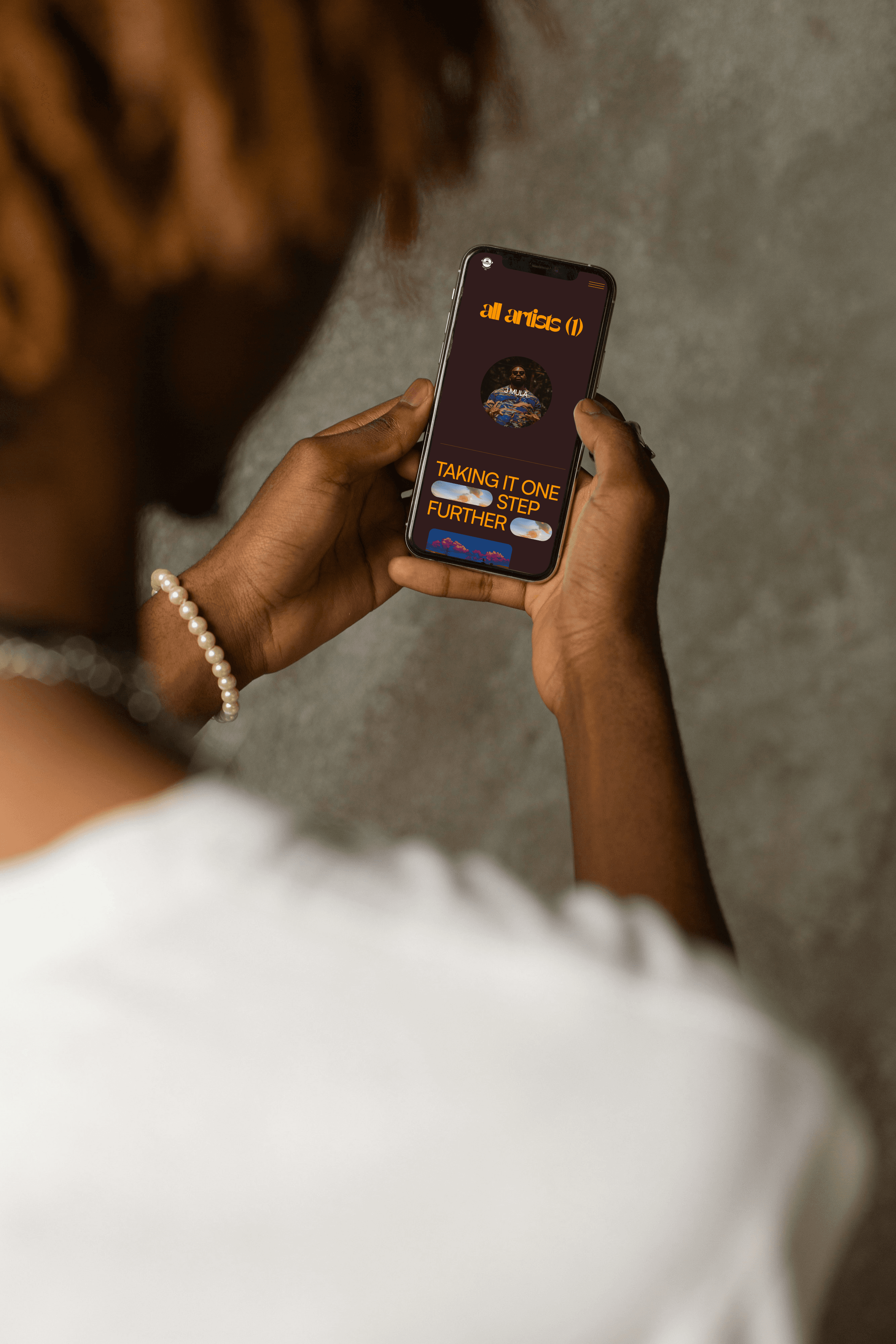 man with pearl bracelet looking down at phone